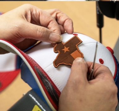 Hands working with a leather patch on a cap